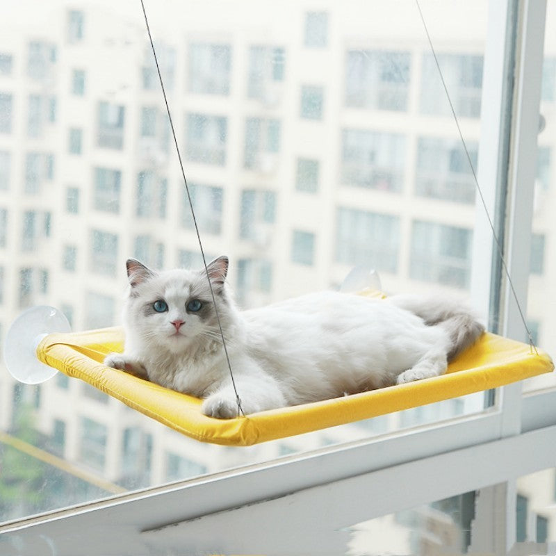 Hangende Kattenhangmat – Zuignap voor Raam met een witte kat die op de gele hangmat ligt.